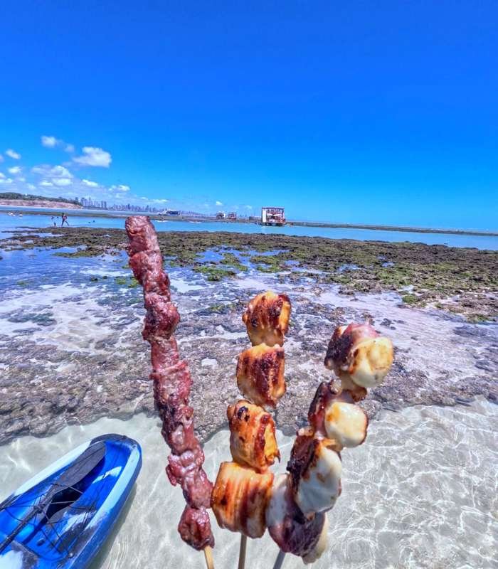 Passageiros comemorando nas Piscinas Naturais do Seixas ao lado do barco